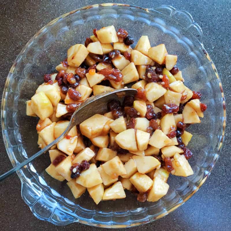 Mincemeat and chopped apple in a glass pie dish ready to be topped with sponge batter.